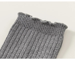 Macro view of grey ribbed kids socks with glitter silver threads and wavy ruffle edges