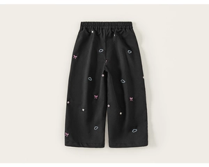Détail du pantalon noir pour fille avec broderies de nœuds roses et de nuages