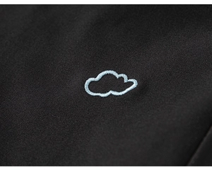 Détail de la broderie nuage bleu clair sur un pantalon cargo noir pour fille