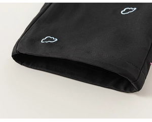 Vue détaillée du pantalon cargo noir avec broderie de nuage et texture du tissu sergé