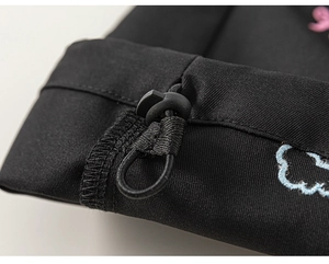 Détail du cordon de serrage avec boucle et broderie de nuage sur un tissu noir épais