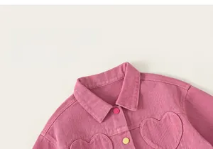 Détail d'une veste en jean rose pour fille avec poches cœur et boutons colorés