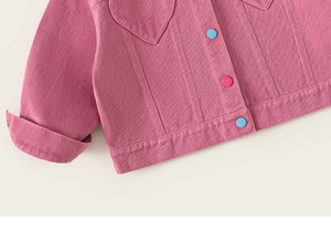 Gros plan d'une veste en jean rose avec boutons colorés et détails de poche en cœur