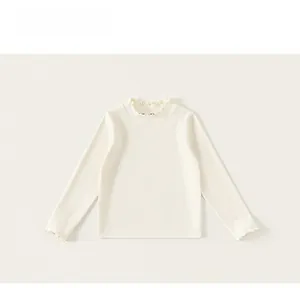 Close-up of ruffles on the collar and cuffs of this beige long sleeve girls top
