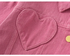 Détail de la veste en coton rose avec poche en forme de cœur et bouton jaune contrasté