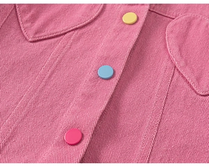 Détail d'une veste en jean rose avec des boutons colorés et des coutures précises