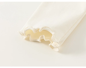 Macro shot of vertical ribbed cotton fabric and ruffled lettuce edge cuff on girl top