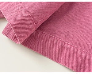 Gros plan sur la texture du velours côtelé rose et les coutures de la veste pour enfant