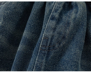 Macro shot of dark blue denim fabric showing double-stitched seams and twill texture