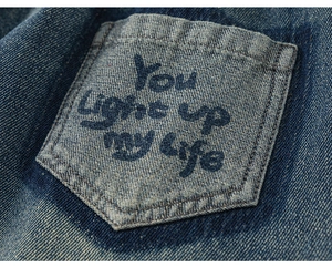 Detail of dark blue denim pocket with You light up my life vintage wash print text