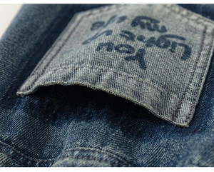 Macro view of blue denim pocket featuring printed text on washed cotton fabric