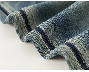 Detailed macro view of striped denim fabric texture and navy blue stitched hem