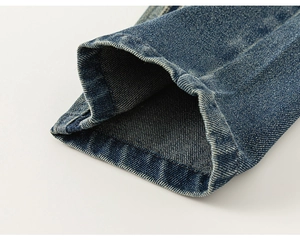 Detailed close-up showing the double-stitched hem and heavy-duty washed denim texture