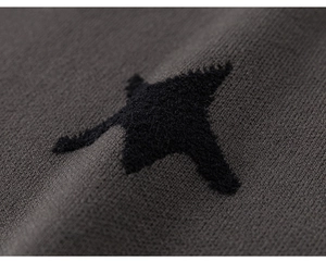 Detailed macro view of black plush star applique on dark grey knit sweater fabric