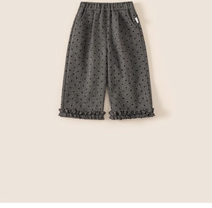 Detail of dark grey kids trousers with heart pattern and elegant ruffled leg openings