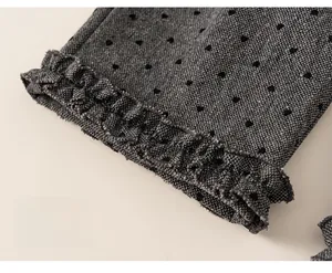 Detail of grey knitted trousers featuring black heart patterns and ruffled hem cuffs
