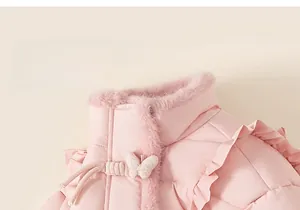 Détail de la veste d'hiver rose pour enfant avec col en fourrure et boutons papillon