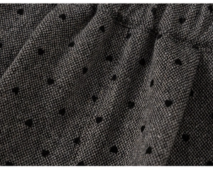 Close-up of textured grey fabric featuring black heart polka dots on girls' trousers