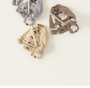 Flat lay of forest style knitted kids cardigans in grey brown and beige with lamb patterns