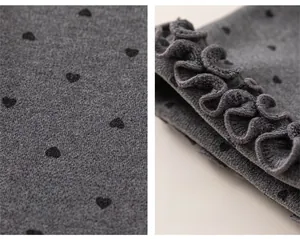 Detail of grey knit fabric with black heart prints and sweet ruffled cuffs on girl trousers