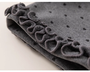 Close-up of girls velvet trousers showing knit texture with heart print and ruffle edges