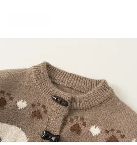 Detail of knit cardigan with horn buttons and brown animal paw jacquard patterns