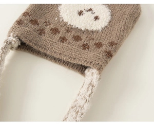 Close-up of brown knitted fabric with dark dots and soft cream plush texture details