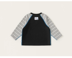 Detail of children striped raglan sleeve shirt with contrast stitching and woven label