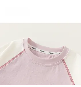 Detailed macro shot of reinforced crew neckline with branded ribbon on striped raglan tee