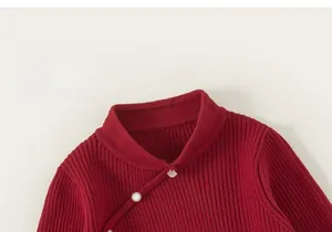 Detailed close-up of dark red ribbed knit sweater featuring vintage diagonal button closure