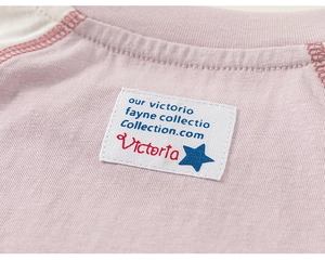 Detail shot of woven label on pink striped cotton long sleeve tee for kids