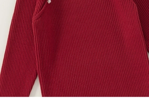 Detailed macro view of deep red ribbed knit sweater fabric with decorative pearl button