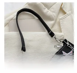 Close-up of a black canvas shoulder bag featuring white stitching and star embroidery