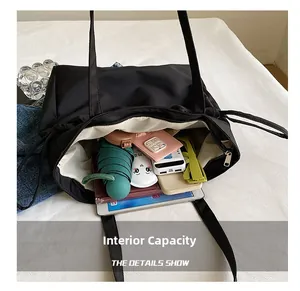 Vista macro que muestra la gran capacidad interior del bolso tote negro con objetos diarios
