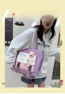 Close-up of color-block tote bag with Hello Baby print and cute plush bear charm