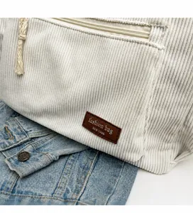 Detail of corduroy bucket bag texture with front zipper pocket and rope handle