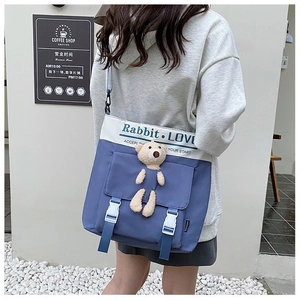 Detail of blue and white canvas crossbody bag featuring a cute bear plush toy and flap design