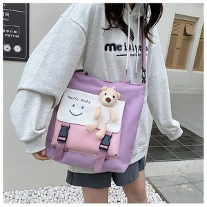 Detail of pink and purple tote bag featuring plush bear and Hello Baby smile graphic