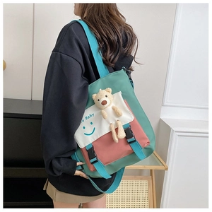 Detail view of the contrast color patchwork tote bag with a cute plush bear accessory