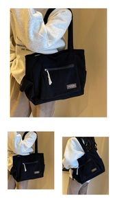 Detail of black corduroy tote bag showing front zipper pocket and brown leather label