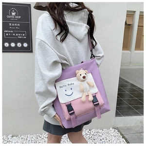 Detail of canvas crossbody bag featuring contrast colors, a bear toy, and 'Hello Baby' print