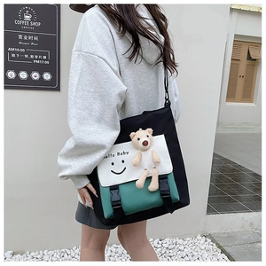 Detail of colorblock canvas tote bag featuring smiley print and 3D plush bear accessory