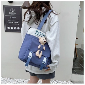 Detail of blue canvas messenger bag with Rabbit print and cute plush bear charm
