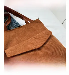 Detail of tan corduroy tote bag showing textured fabric and front flap pocket design
