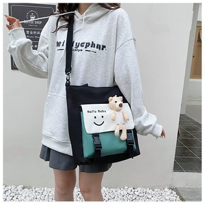 Detail of color-blocked canvas crossbody bag with smiley face print and plush bear pendant