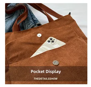 Brown corduroy tote bag detail showing external pocket with magnetic snap and smartphone