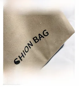 Detail view of khaki canvas tote featuring bold FASHION BAG text and woven texture