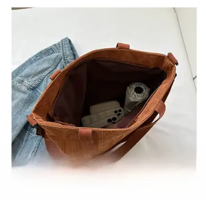 Internal view of a brown corduroy tote bag showing large capacity with umbrella and phone