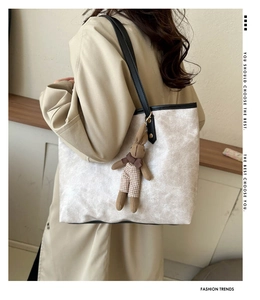 Detail of cream marbled tote bag with black leather straps and a brown rabbit charm