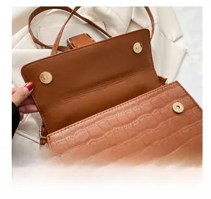 Detail of the brown crocodile pattern shoulder bag featuring dual hardware magnetic buckles
